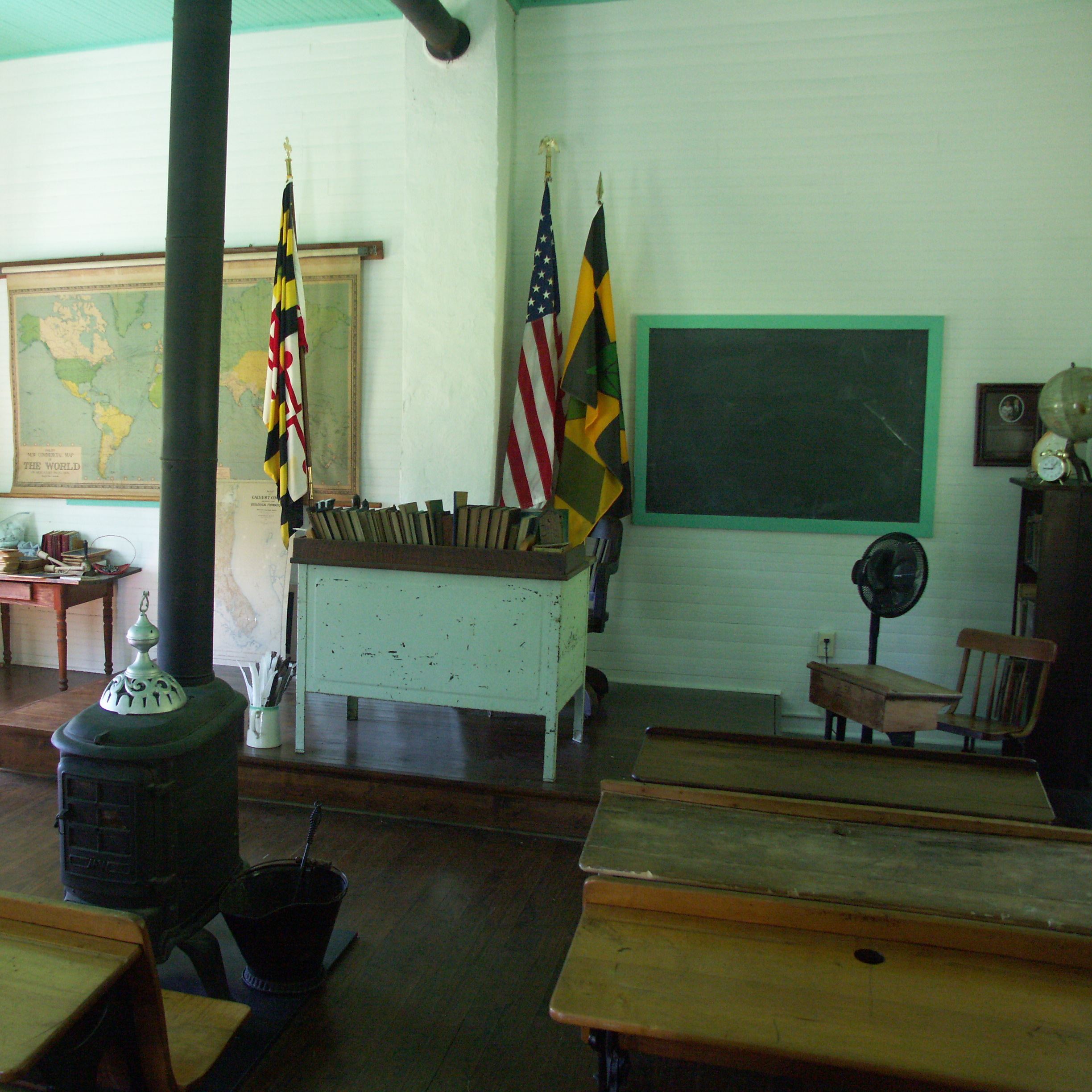 Inside of the One Room Schoolhouse with desks, a furnace and chalkboards