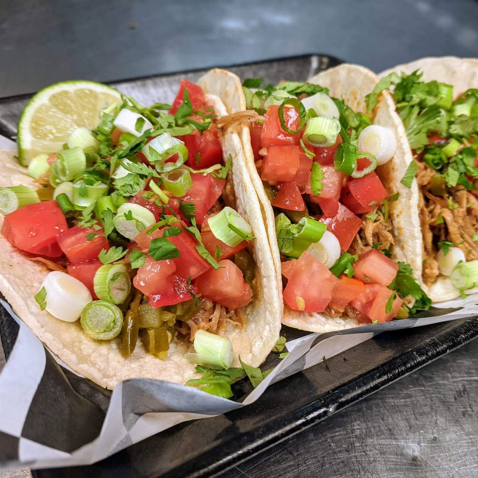Street tacos with tomato's, onions and garnished with a lime