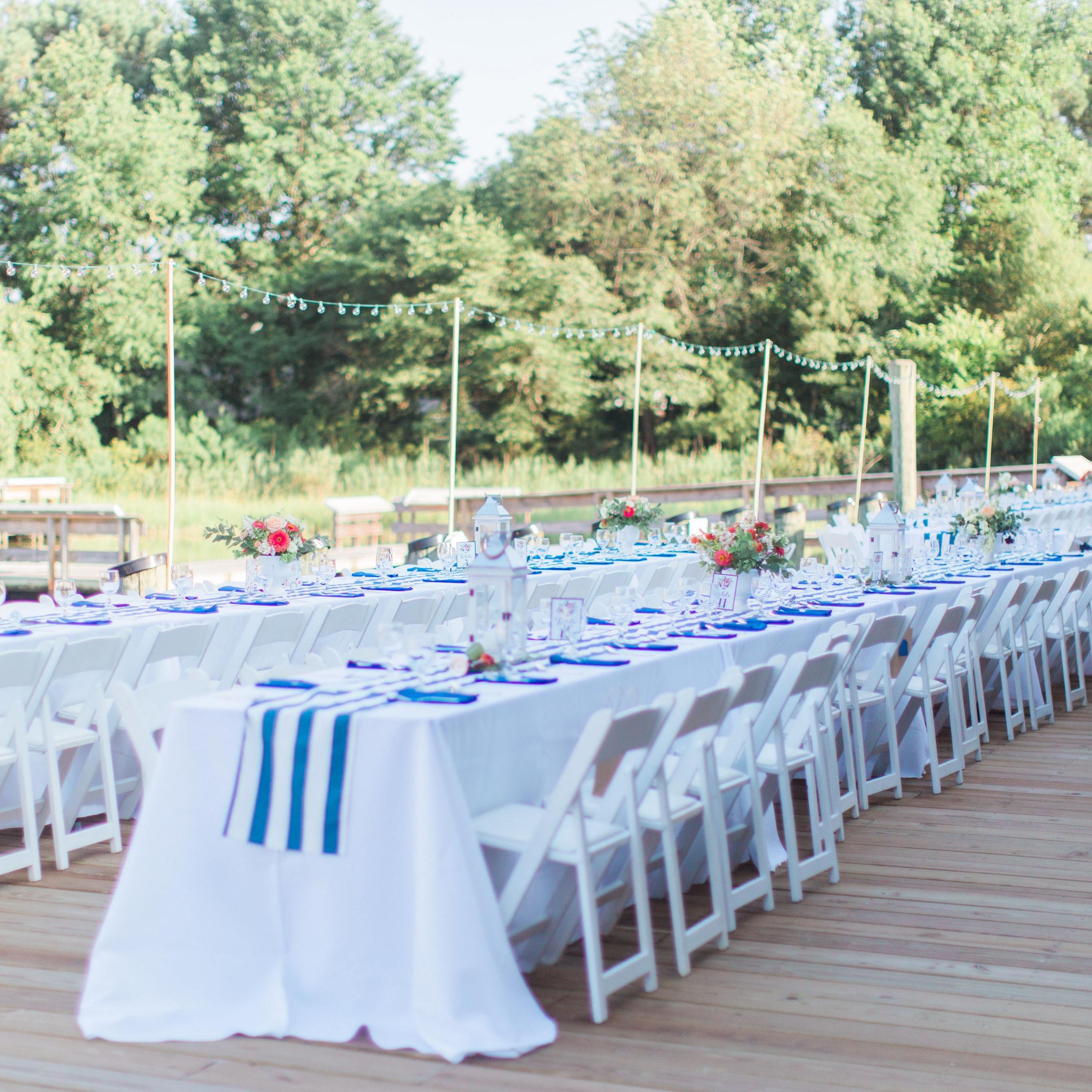 Wedding dining tables with white table clothes and royal blue accents overlooking the water