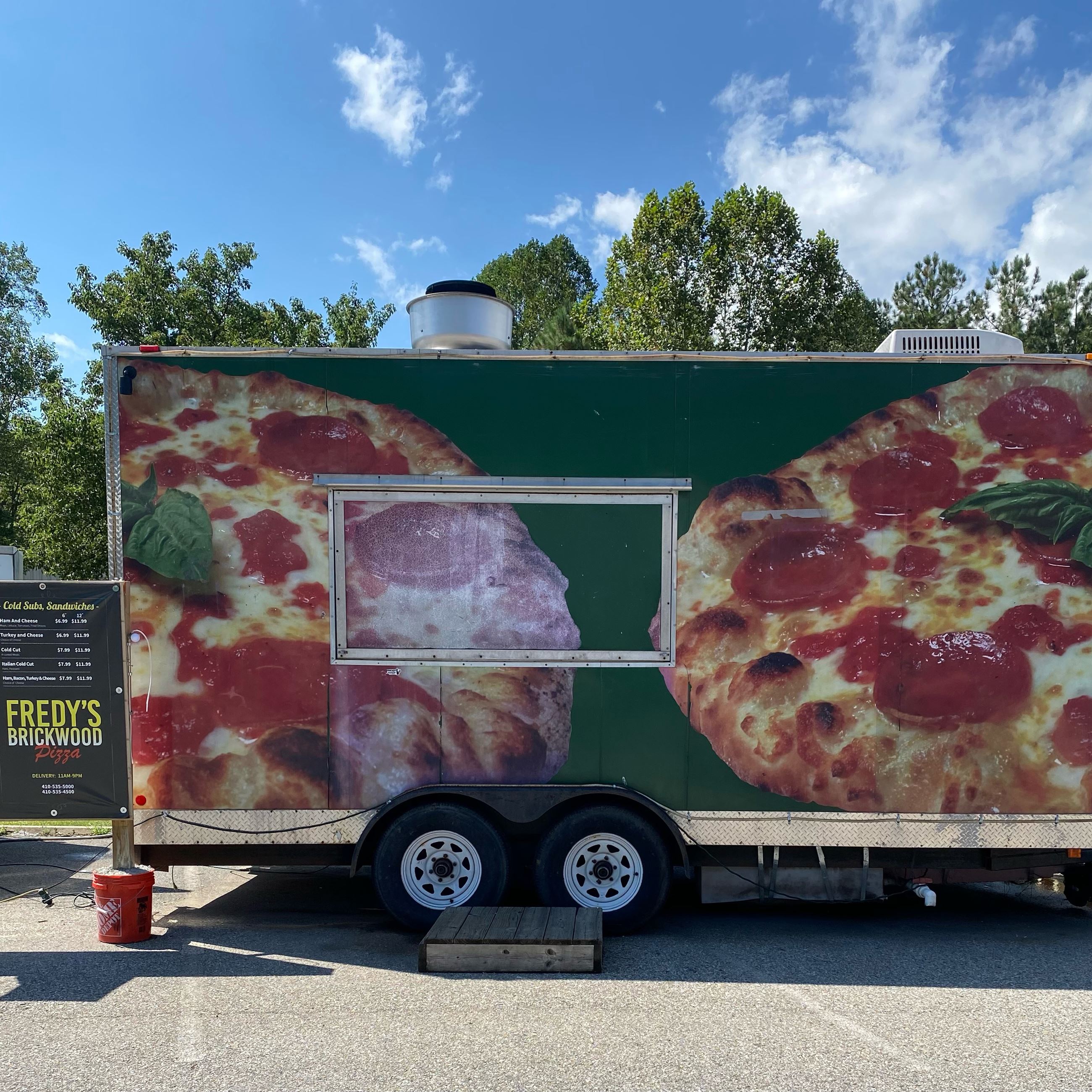 Fredy's Brickwood Pizza food truck with menu sign out front