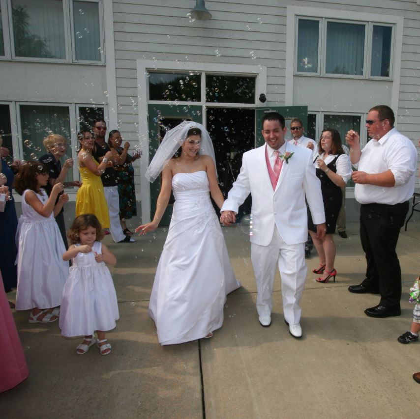 Bride and groom walk through bubbles blown by guests