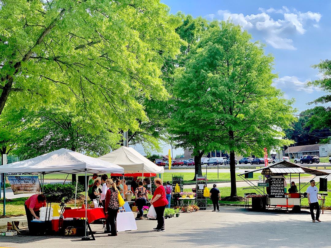 Tents selling fresh produce with patrons walking around