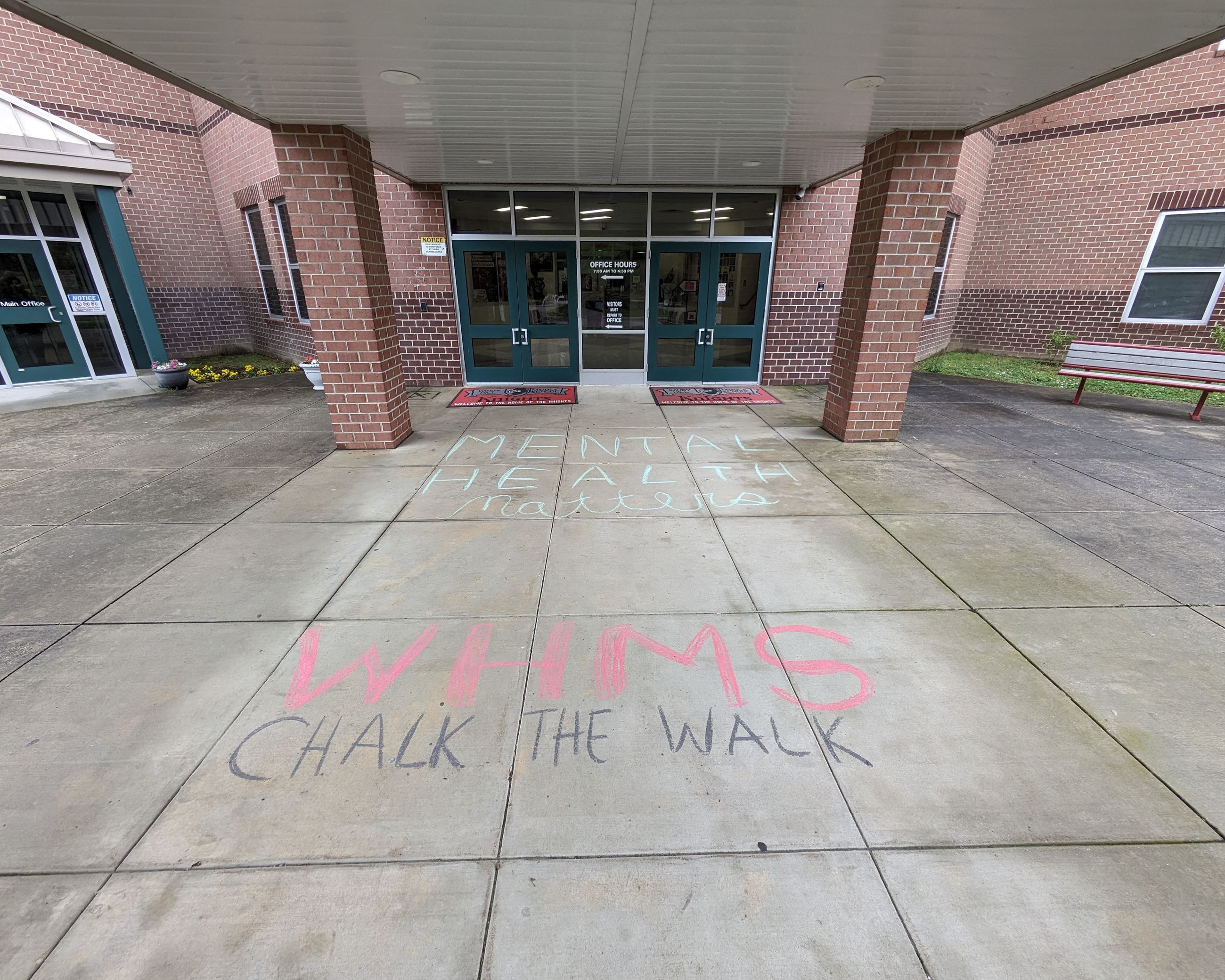 Chalk text in front of Windy Hill Middle School reads "Mental Health Matters. WHMS Chalk the Walk