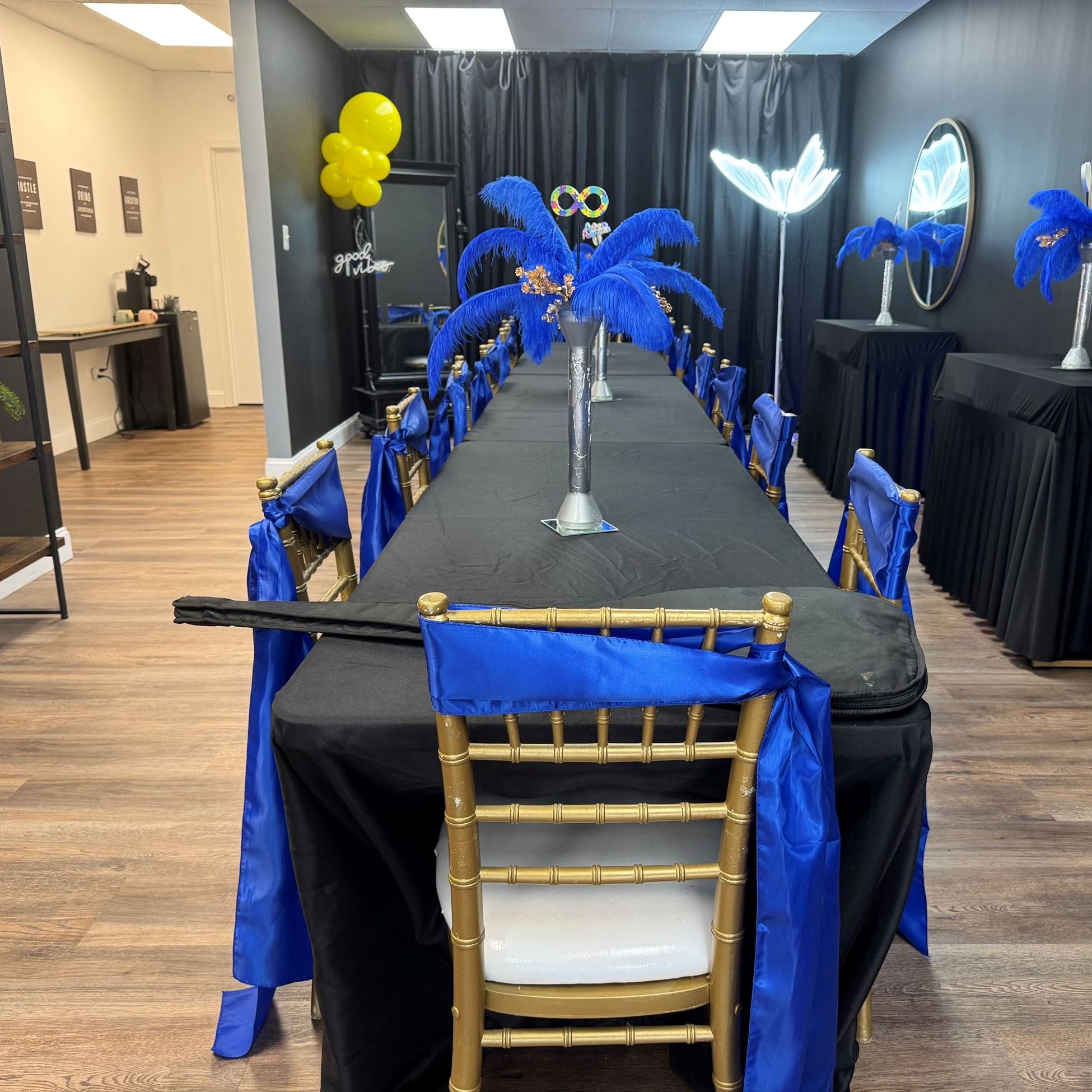 long table with black tablecloth and chairs with blue ribbon
