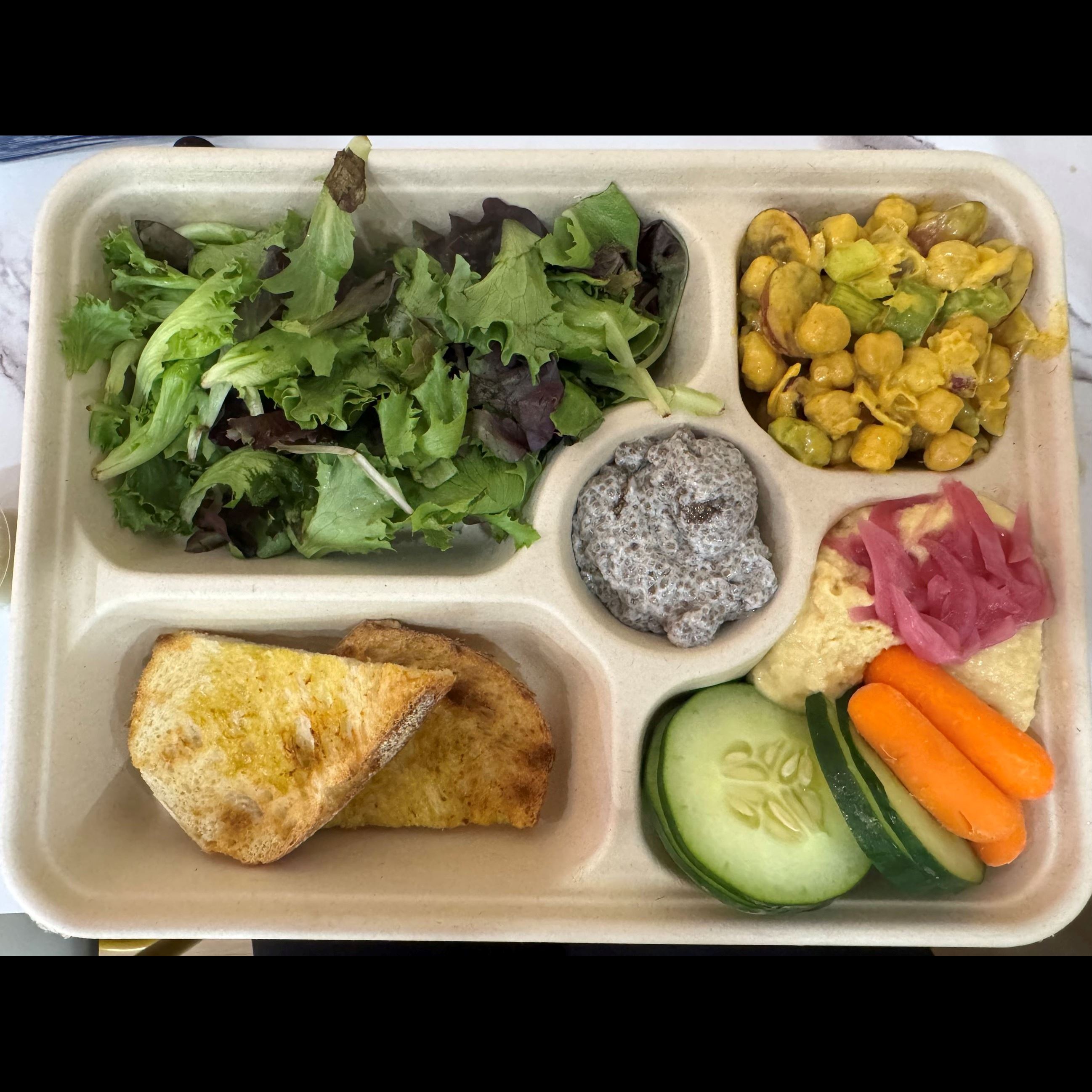 divided plate with mixed greens and cut vegetables
