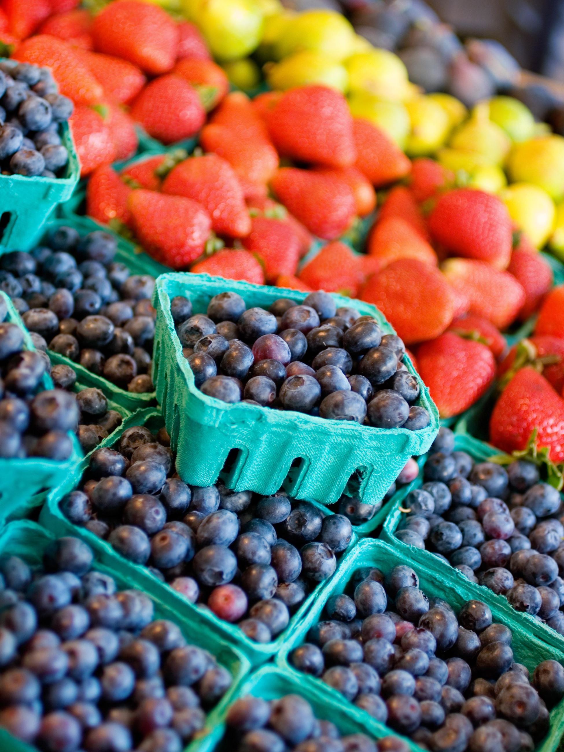 Blueberries in containers with strawberries in the background